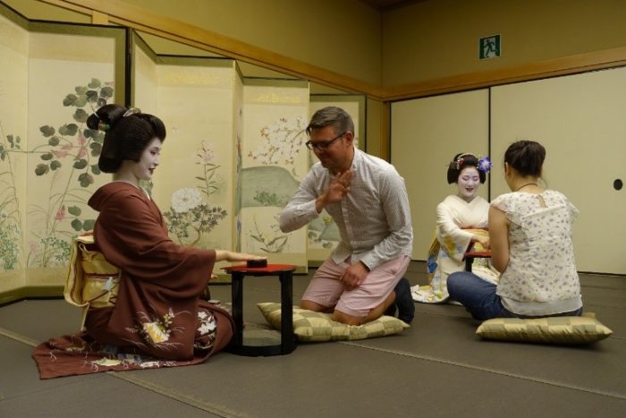 A geiko (left) and maiko (right) play games with fellows.